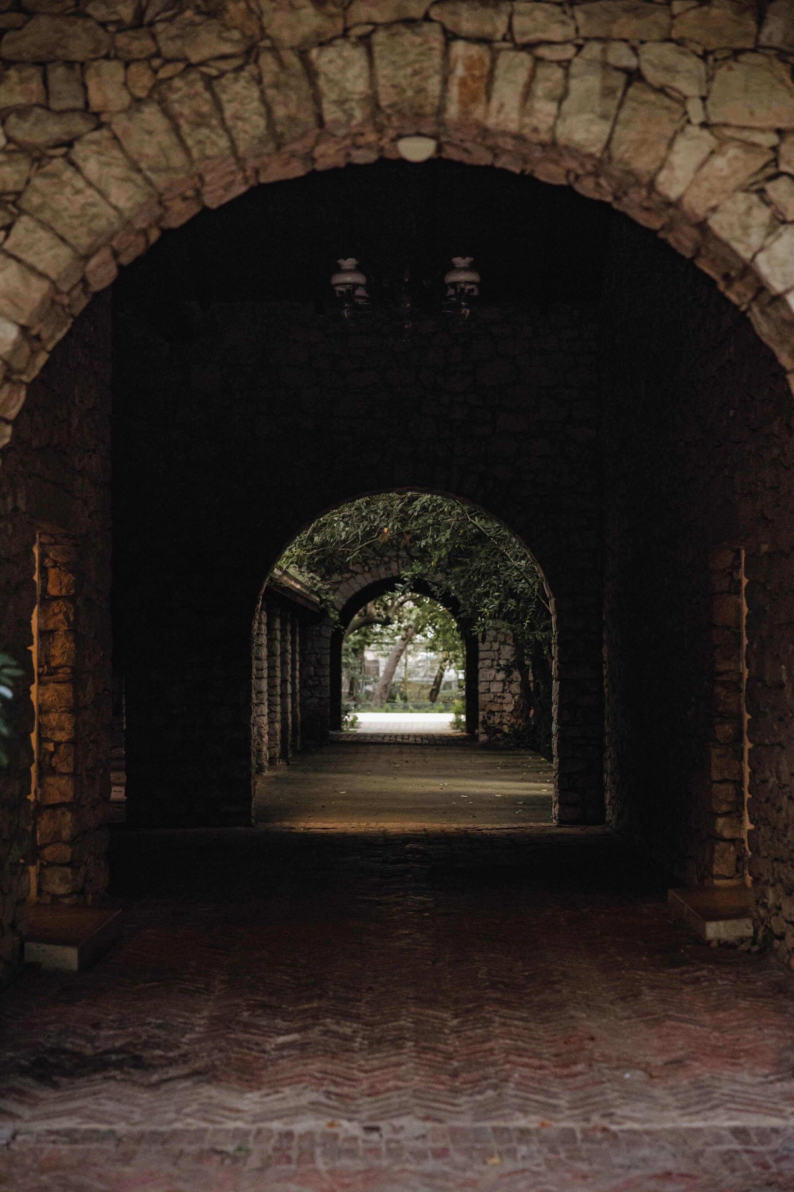 An arched stone corridor with a bench at the end.