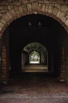 An arched stone corridor with a bench at the end.