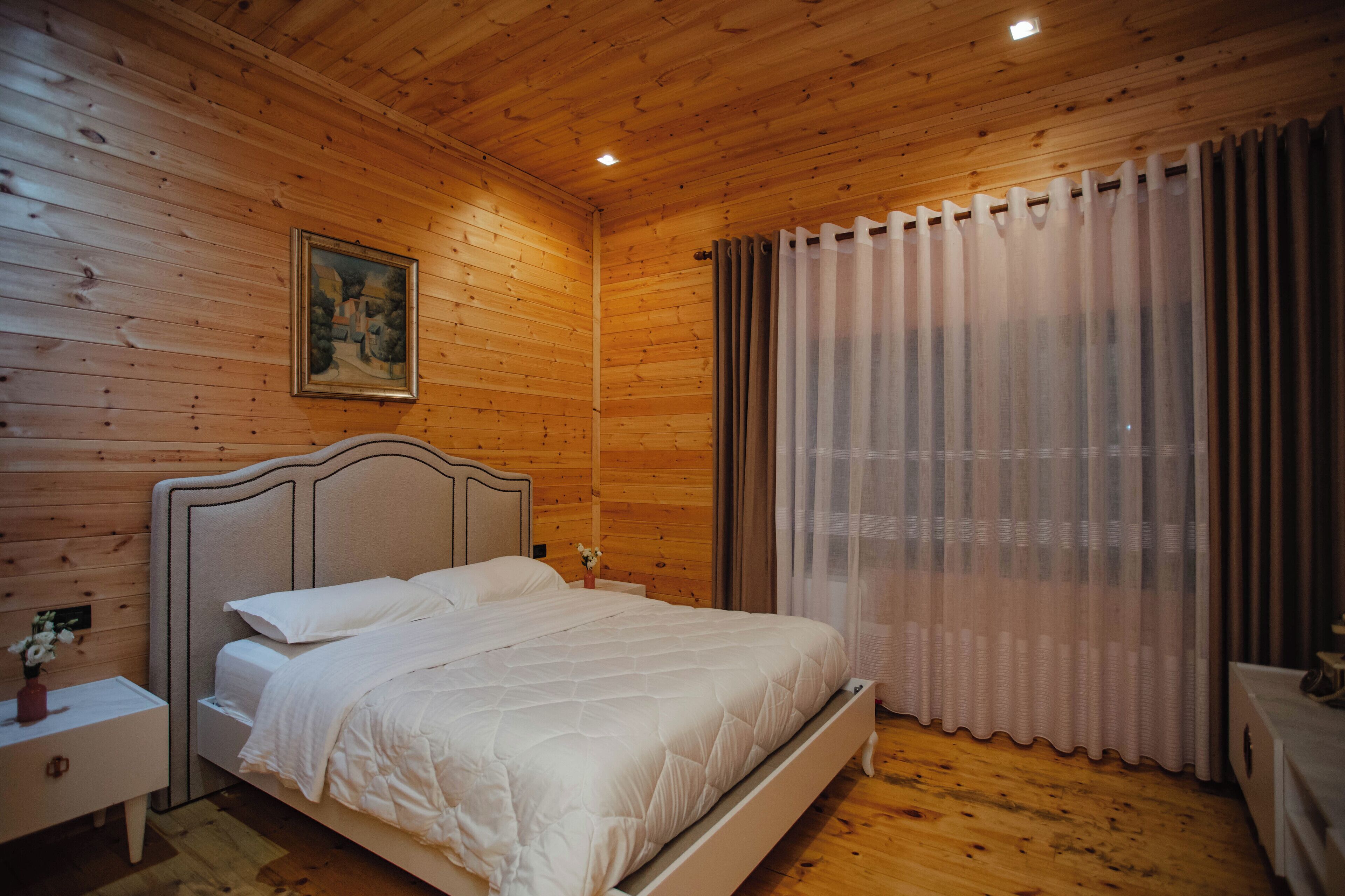 Un dormitorio con paneles de madera, una cama, una mesita de noche y un cuadro en la pared.