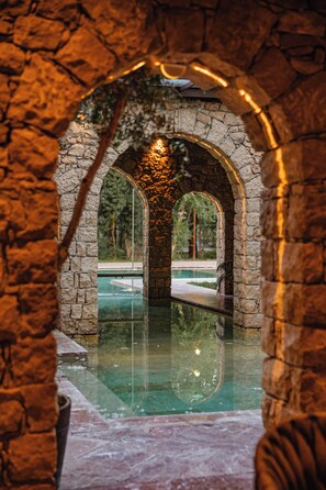 An indoor swimming pool with stone arches and a clear view of the surrounding area. - Hoteli Gjuetise (Shengjin)
