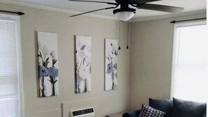 Een woonkamer met een donkergrijze bank, een salontafel en drie schilderijen aan de muur.