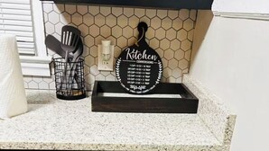 Een keuken met een aanrecht, een afwasschaal, een bord met keukenomrekeningen en een vaatwasser.