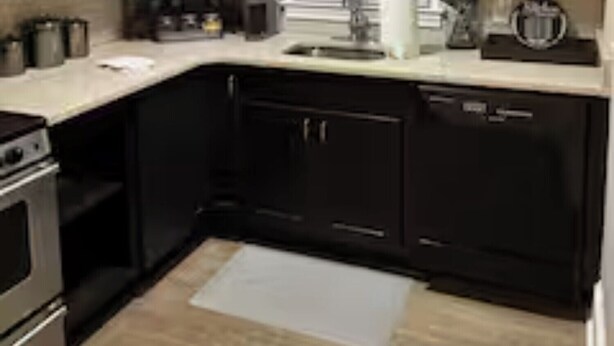 Een keuken met donkere kastjes, een roestvrijstalen fornuis, een spoelbak en een raam met zonwering.