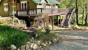 Eine Lodge mit einem grünen Dach, einer Holzterrasse und einer Treppe, die zu einem überdachten Bereich führt.