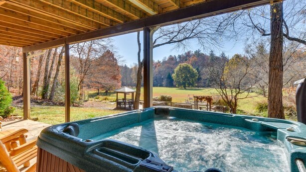 Ein Whirlpool mit Holzterrasse und Blick auf einen Park mit Bäumen und einem Pavillon.