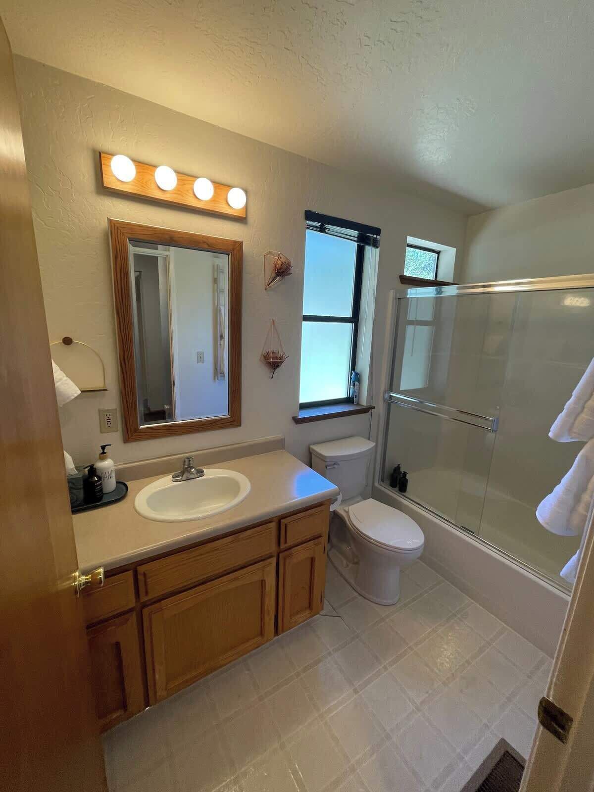 A bathroom with a sink, mirror, toilet, and glass shower.