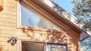 A wooden cabin with a glass door leading to a living area with a sofa, TV, and dining table. - West Village-Large Lovely Private Home in Kirkwood (Kirkwood)