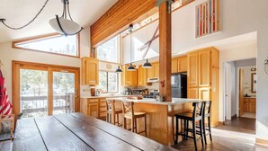 A spacious kitchen with wooden cabinets, a central island with bar stools, and large windows allowing natural light. - West Village-Large Lovely Private Home in Kirkwood (Kirkwood)