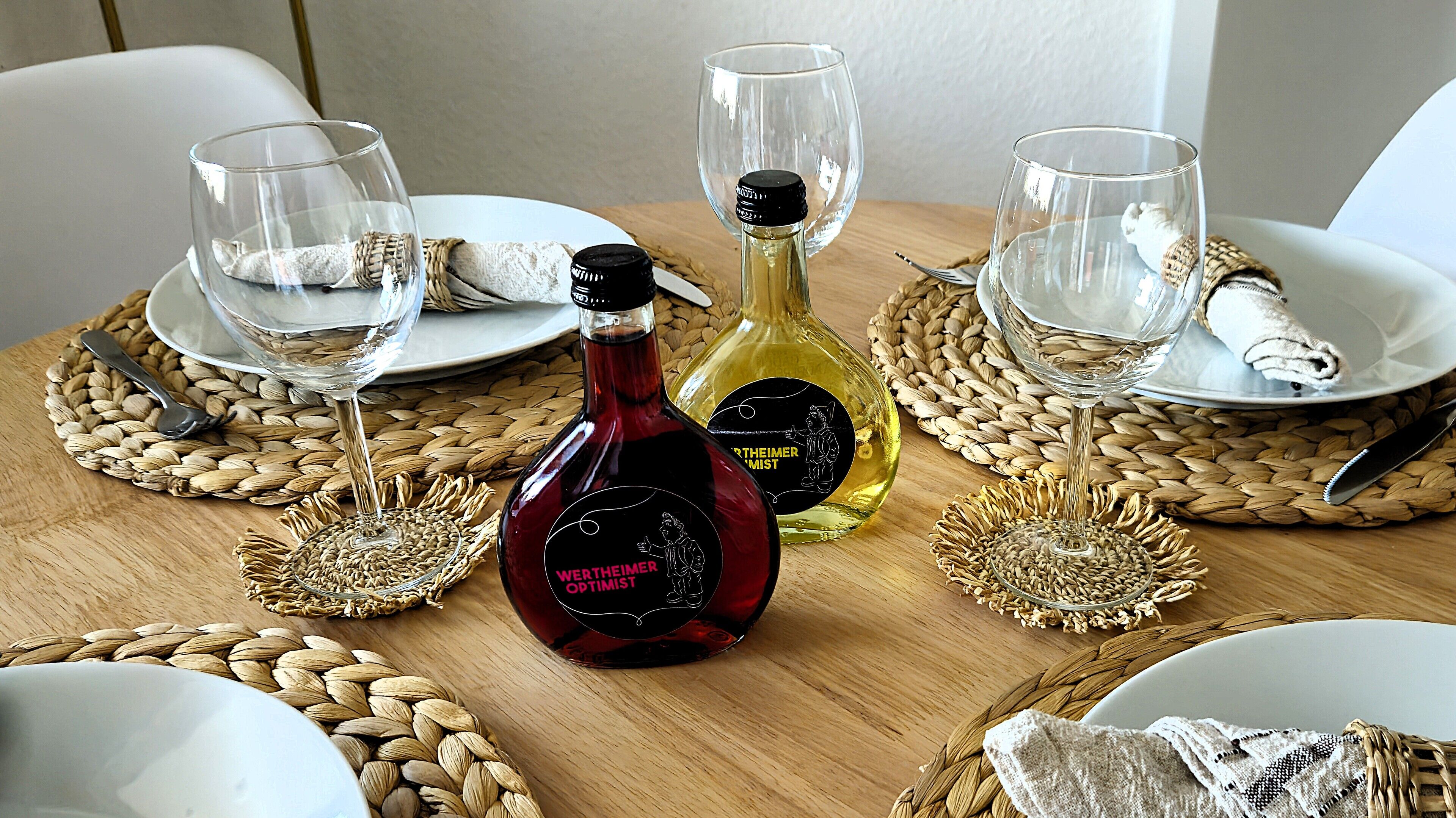 Une table à manger dressée avec des assiettes, des verres et des bouteilles de vin.