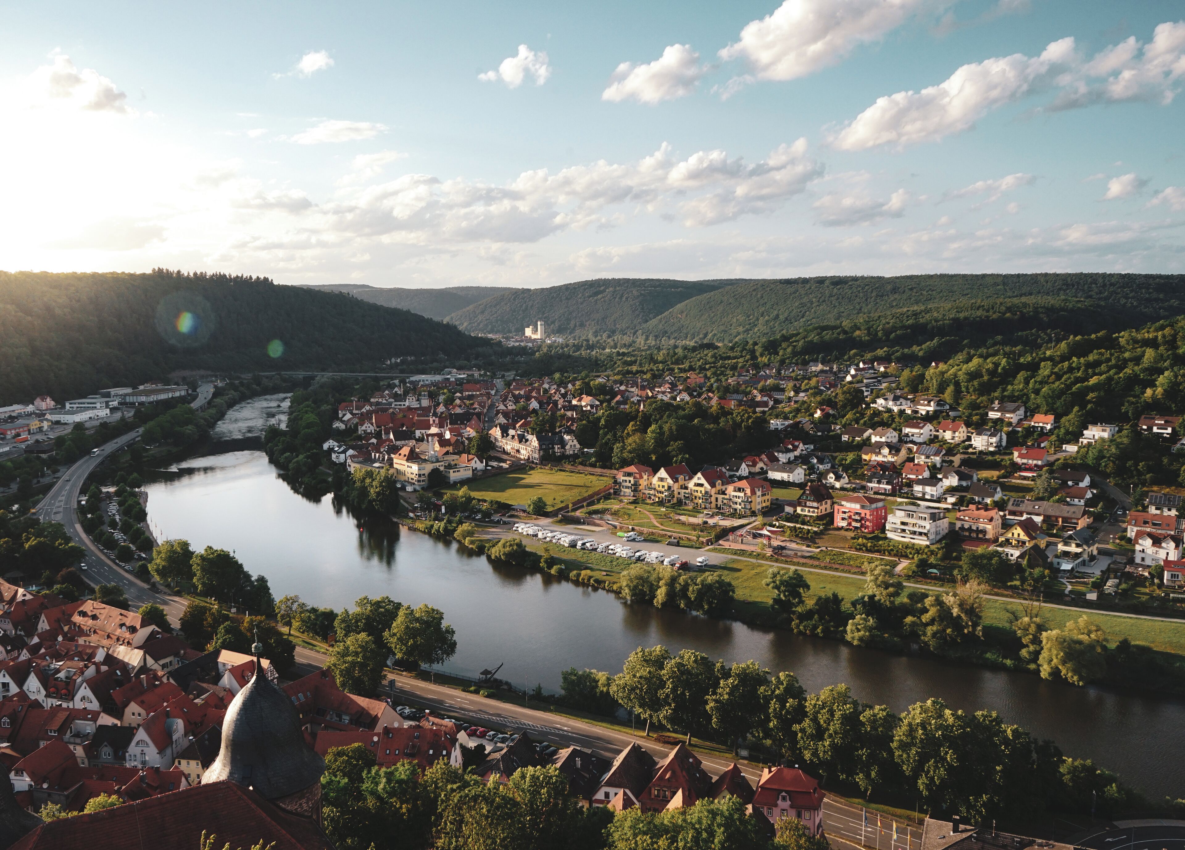 Une ville riveraine dotée de bâtiments historiques, d’une église imposante et d’un château qui se profile à l’arrière-plan.