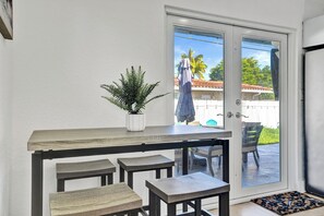 A modern kitchen with a wooden countertop, a potted plant, and a sliding glass door leading to an outdoor area.