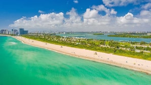 A coastal cityscape with a wide beach, clear turquoise waters, and a skyline of high-rise buildings. - ★Miami Spacious Retreat 10 ninutes to Ocean • BBQ Pool Firepit• Sleeps 20+★ (North Miami Beach)
