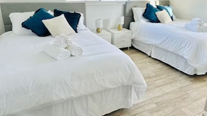 A hotel room with two beds, white bedding, and blue pillows. There are towels on the beds and a window with a view of greenery. - ★Miami Spacious Retreat 10 ninutes to Ocean • BBQ Pool Firepit• Sleeps 20+★ (North Miami Beach)