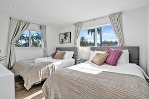 A hotel room with two beds, a nightstand, a lamp, and a view of palm trees. - ★Miami Spacious 4BR Retreat •10 min to beaches• BBQ Firepit• Backyard★ (North Miami Beach)
