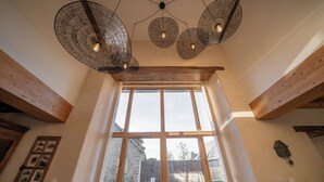 A room with large windows, wooden beams, and a ceiling fan with light bulbs. - Les CLEFS de la Baie- Charming house for 12 people in the Bay of Mont Saint Michel (Céaux)