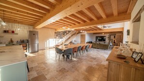 A spacious kitchen with a large island, wooden beams, and a staircase leading to an upper level. - Les CLEFS de la Baie- Charming house for 12 people in the Bay of Mont Saint Michel (Céaux)