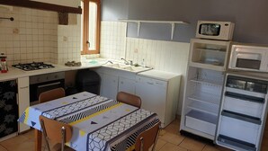 A compact kitchen with a dining table, a microwave, a dishwasher, and a refrigerator. - Country house - Ideal for a team of workers (Nérac)
