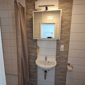 Ein Badezimmer mit einem weißen Waschbecken, einem Spiegel und einer Duschvorhang.