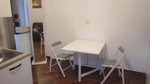 A small, white dining table with four chairs in a compact kitchen area. - Home Colors Apartment (Genova)