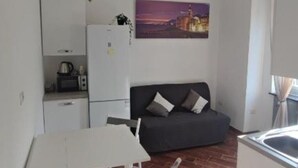 A compact living space with a kitchenette, a dining area, and a sofa. - Home Colors Apartment (Genova)