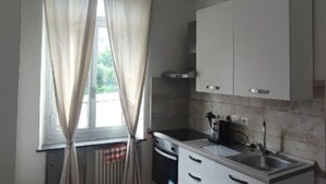 A kitchen with a window, curtains, a sink, and cabinets. - Home Colors Apartment (Genova)