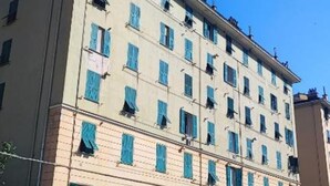 A multi-story building with a beige facade and blue shutters on the windows. - Home Colors Apartment (Genova)
