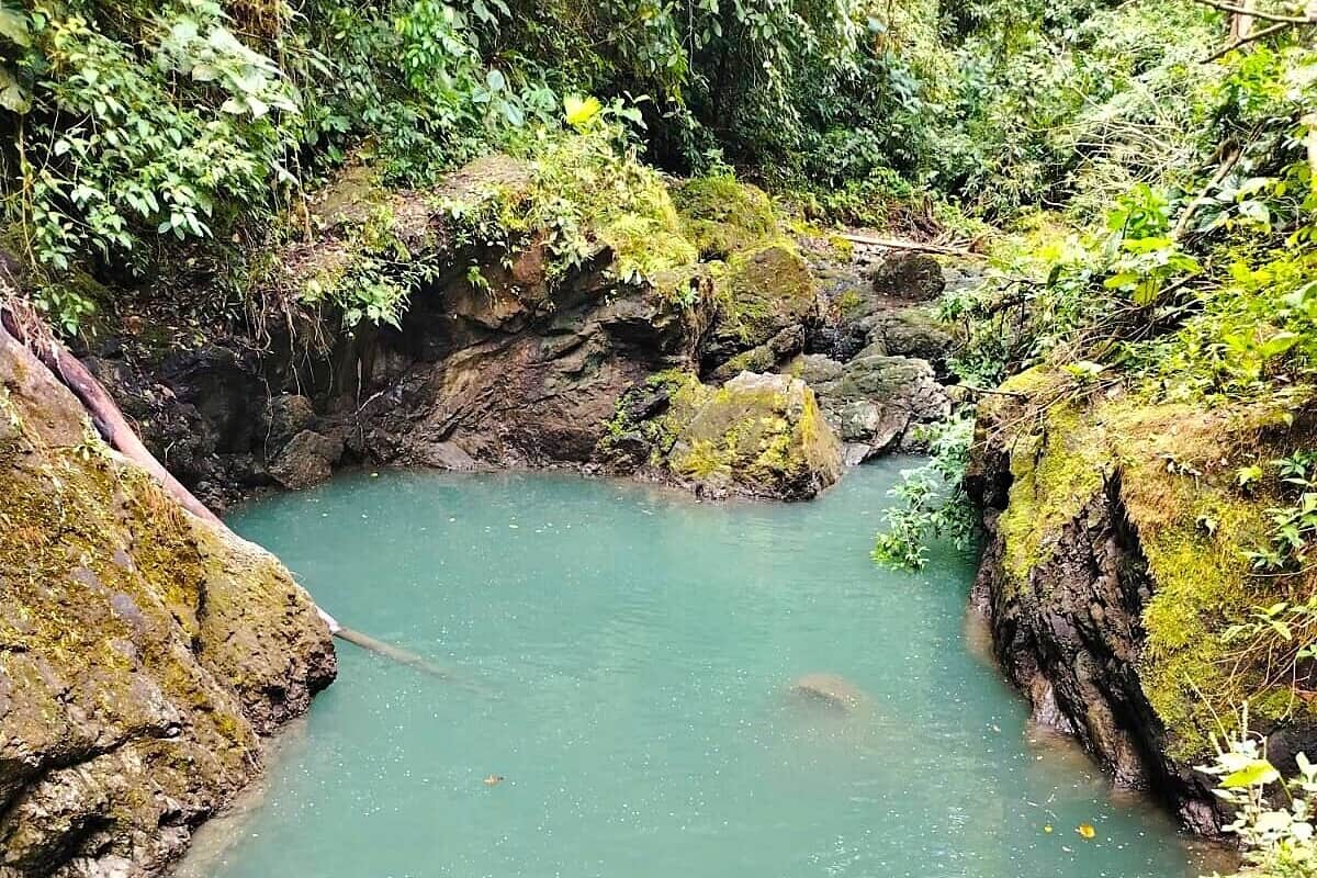 A natural water body surrounded by rocky terrain and dense vegetation.