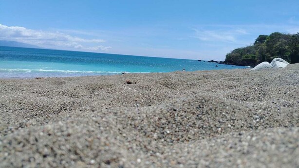 A pebbled beach with a clear view of the ocean and distant land. - Corcovado Pura Vida Stays (Puerto Jiménez)