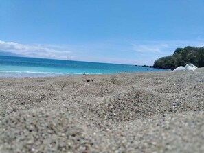 A pebbled beach with a clear view of the ocean and distant land. - Corcovado Pura Vida Stays (Puerto Jiménez)