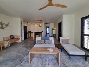 Een moderne woonkamer met een houten salontafel, twee banken en een plafondventilator.