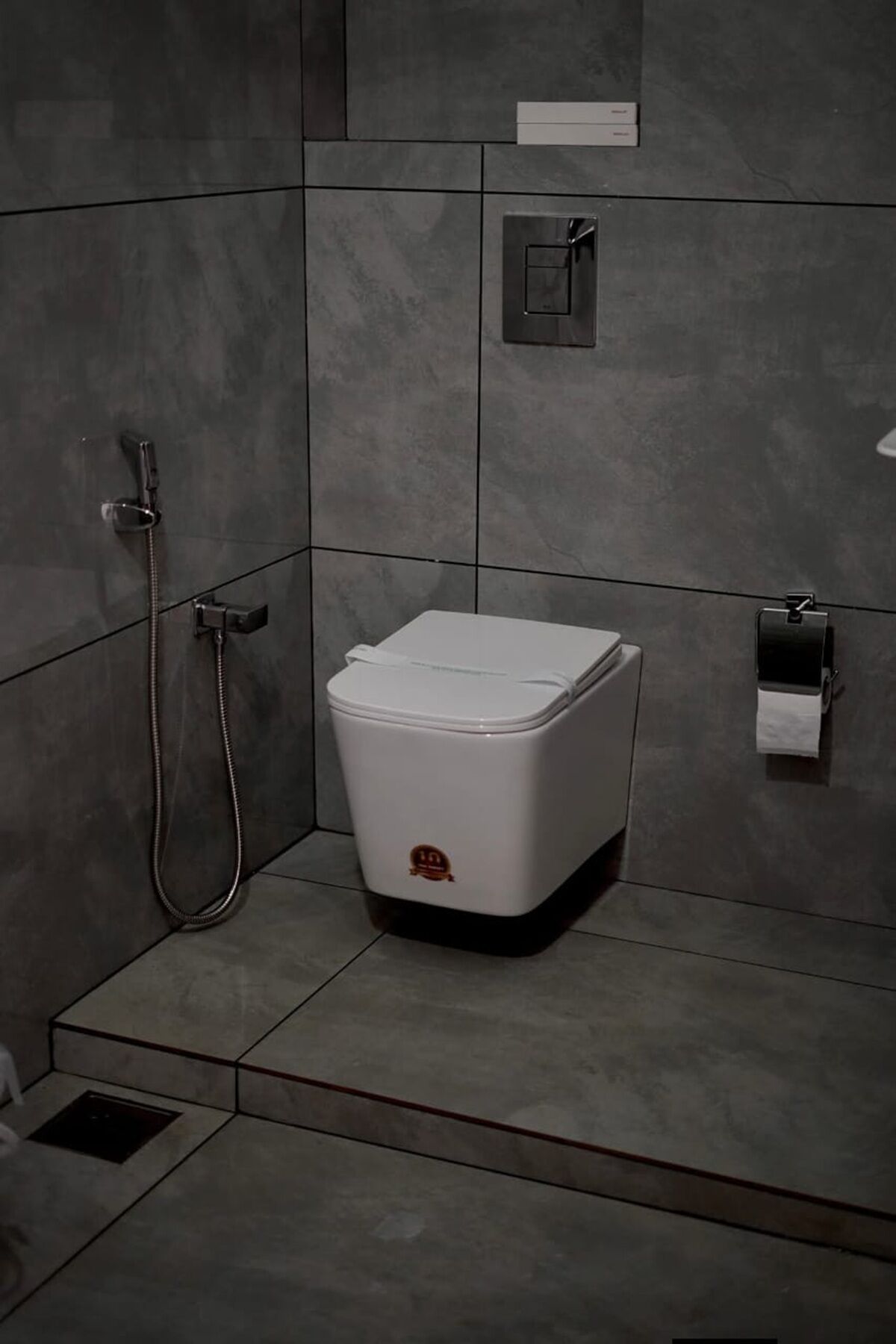 Une petite salle de bain avec des toilettes blanches, une douche et un distributeur de serviettes.