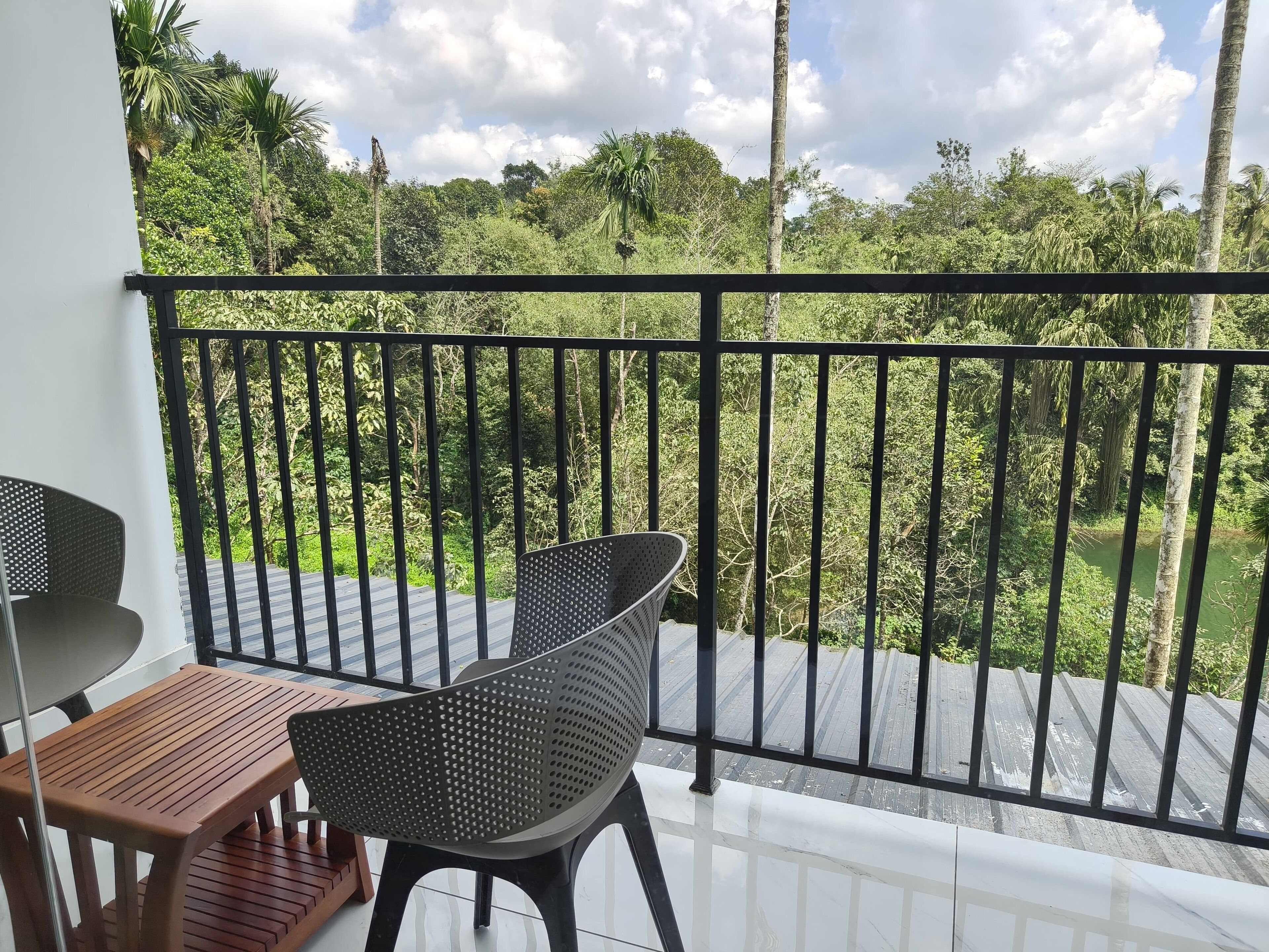A balcony with a black metal railing, a wooden table, and a plastic chair.