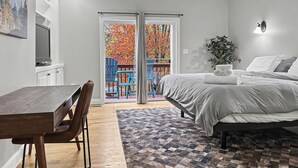 Quarto com cama, escrivaninha e cadeira. Janela com vista para árvores.