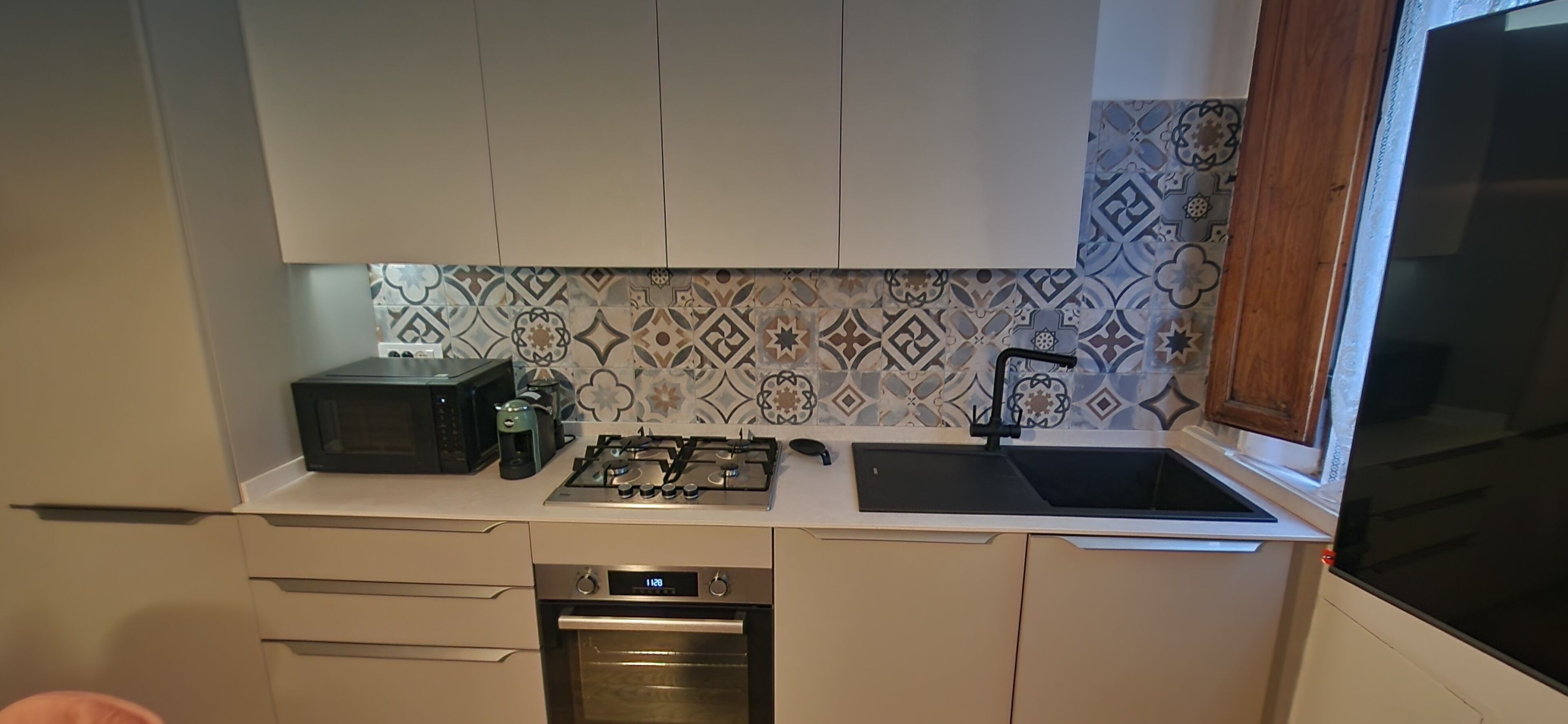 Een kleine keuken met een magnetron, gasfornuis, oven en spoelbak.