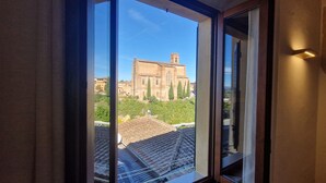 A view through a window of a building with a tiled roof and a large structure in the background. - Casa Siena Bruna, typical central apartment with breathtaking views (Siena)