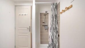 Une salle de bain avec une douche, un porte-serviettes et une porte.