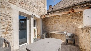 Un bâtiment en pierre avec un toit en tuiles, une table et deux chaises dans la cour.