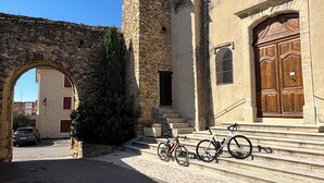 Un bâtiment en pierre avec une tour, une porte en bois et un vélo garé devant.