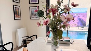 Une table avec une bouteille de vin, des verres, un menu et un vase de fleurs.