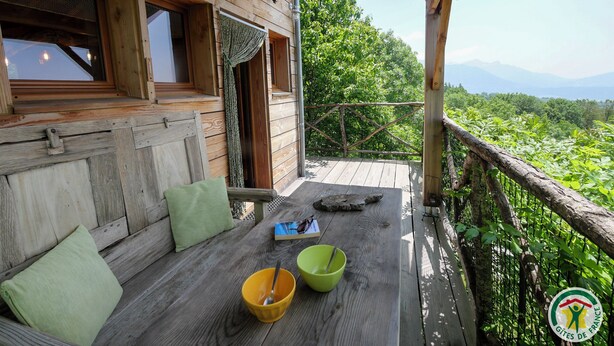 Une terrasse en bois offrant une vue sur une végétation luxuriante et des montagnes.