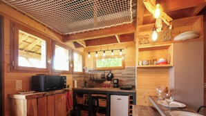 Une cuisine compacte dotée de meubles en bois, d’un four à micro-ondes, d’une machine à café et d’un évier.