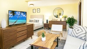 Ein Hotelzimmer mit Bett, Fernseher, einem Holzschrank, einer Couch und einem Couchtisch.