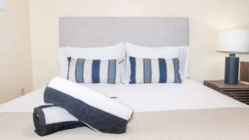 A neatly made bed with striped pillows and a rolled-up blanket.