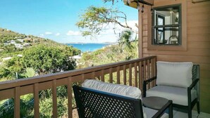 Ein Balkon mit Blick auf das Meer, ein Stuhl und ein Tisch.