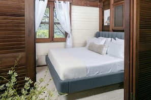 A bedroom with a bed, curtains, and a window. - Oceanview Cottage Walk to Beach & Restaurants (Cruz Bay)