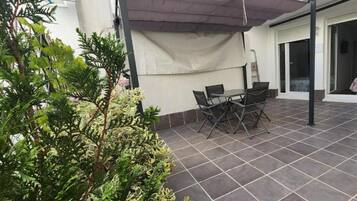 Un espace extérieur aménagé en terrasse, avec une table et des chaises, entouré de plantes en pot.