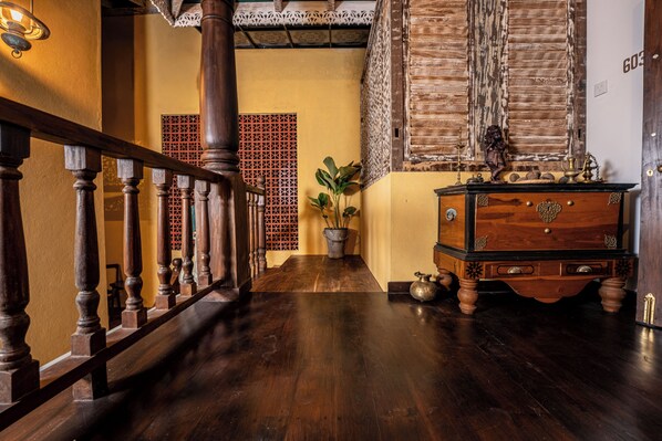 A wooden staircase with a railing, a potted plant, a wooden chest of drawers, and a patterned wall. - Beautiful villa with pool in charming Galle (Galle)