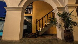 Una imponente escalera con barandal de madera que conduce a una zona del segundo piso con estanterías y vistas al exterior.