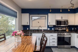 A modern kitchen with white cabinets, a stainless steel stove, and a large window.