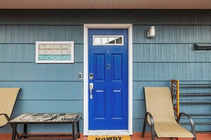A blue door with the number 2, a sign indicating coordinates, and two chairs outside.